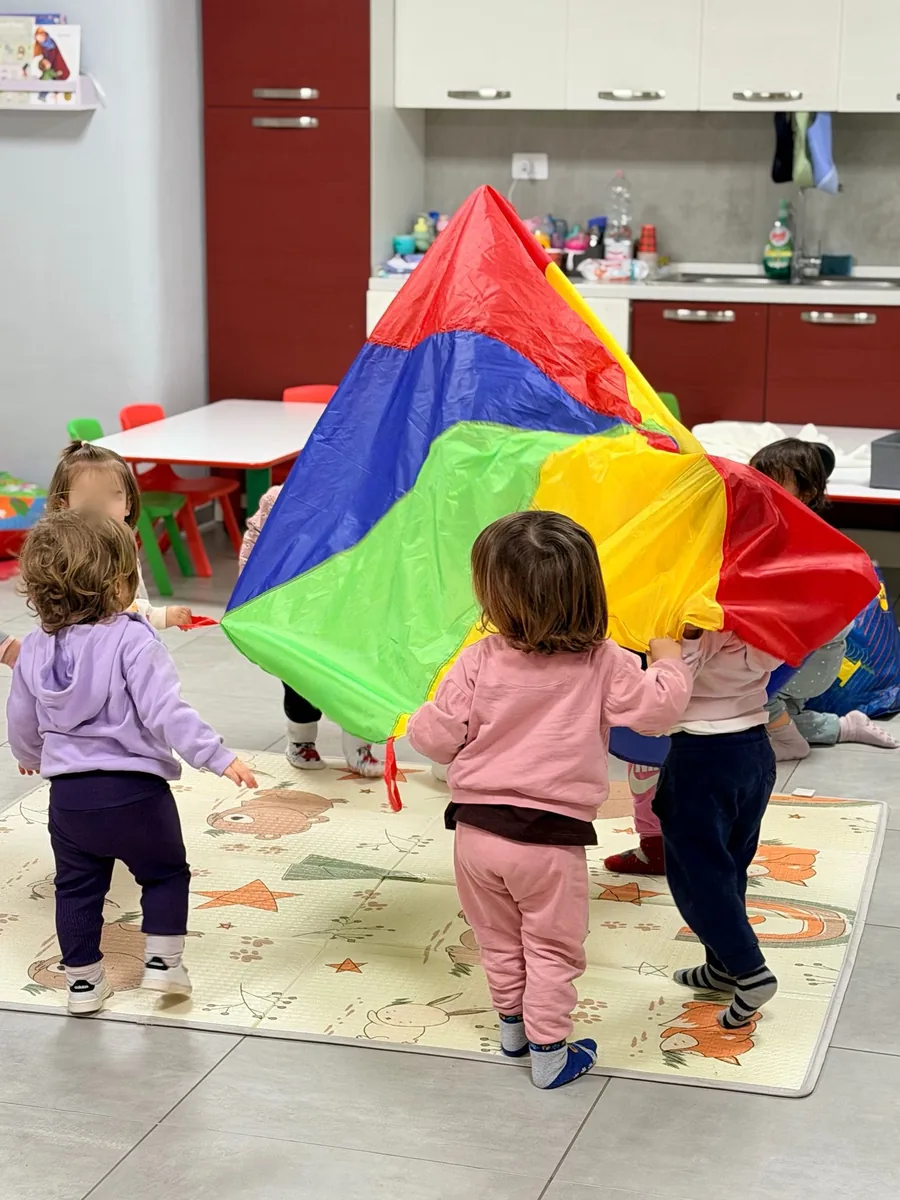 Bambini piccoli giocano con un grande telo colorato durante Crescere in Movimento